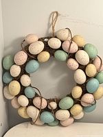Full view of the egg wreath showing densely arranged speckled egg ornaments in pastel colors on a moss covered base with jute hanging loop.
