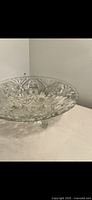 Clear glass decorative bowl on a pedestal, showing detailed pressed starburst and geometric patterns on the bowl surface.