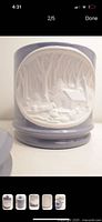 Front view showing the detailed white relief cabin scene on light purple ceramic cookie jar.