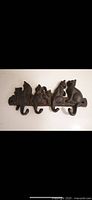 Cast iron key hanger depicting four cats on a horizontal base with four hooks, showing surface rust and patina.