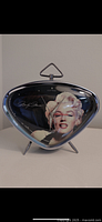 Front view of triangular Marilyn Monroe clock showing image and clock hands.