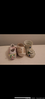 Front view of three small porcelain decorative shoes showing floral designs and colors.