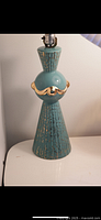 Full view of the turquoise and gold ceramic lamp showing its shape and socket at top