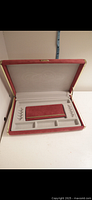 Opened jewelry box showing interior compartments and removable red velvet tray placed in front of box.