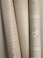 Photo of three rolled wallpapers showing different patterns and textures.