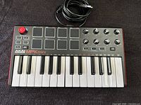 Full view of Akai Professional MPK mini keyboard with USB cable coiled above it.