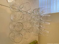 Overview of 19 clear wine glasses including stemless and stemmed types arranged on a flat white surface.