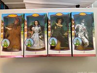 Full view of all four boxed dolls: Cowardly Lion, Dorothy, Scarecrow, Tin Man side by side.