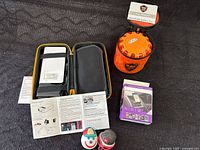 Overview of all items in the lot laid out, including the jump starter in case, roadside safety discs, jack-in-the-box antenna balls, and instruction manuals.