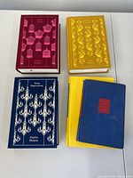 Five hardcover books arranged showing decorative covers and colors including red, yellow, and blue.
