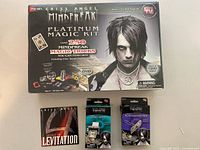 Photo of Criss Angel Mindfreak Platinum Magic Kit in original sealed packaging alongside the Secret to Levitation DVD and two smaller opened Criss Angel magic trick packages (Money Printer and Penetration Pen).