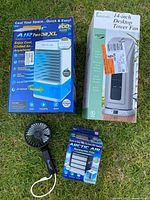 Lot contents showing Arctic Air Pure Chill XL boxed cooler, 14-inch desktop tower fan boxed, handheld portable fan, and Arctic Air replacement filter box.