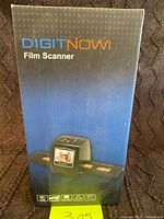 Front of retail box showing DigitNow! Film Scanner branding and image of the device with inserted film strips.