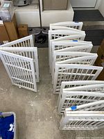 Overhead view of four white wood folding gates with vertical slats, aligned on floor indoors.