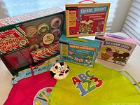 Photo of boxed Melissa & Doug kids food toys and three kids aprons including Christmas Cookie Making, Wash My Underpants, Cheese Please!, and Ice Cream Crazy sets