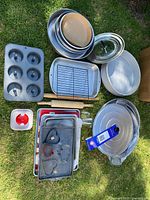 Top view of a variety of bakeware including pans, wire cooling rack, cookie cutters, rolling pin, and glass pie dish
