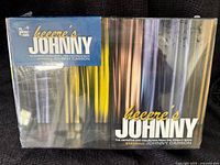 Front view of the definitive Johnny Carson DVD box set in shrink wrap with title and curtains design.