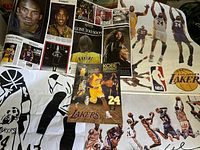Photo showing multiple Kobe Bryant posters, including tribute collages, and black and white wall/window stickers with Lakers designs and Kobe faces.