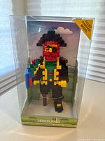 Full view of clear display case containing the glued Lego pirate model on Legoland base