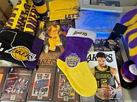 A collection of Lakers memorabilia including DVDs, magazines, a stocking, apparel, and posters with player imagery.