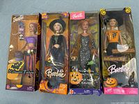 Four Barbie Halloween themed dolls in original packaging. Dolls are Halloween Fortune, Halloween Star, Halloween Enchantress, and Halloween Hip. Packaging shows visible wear but unopened.