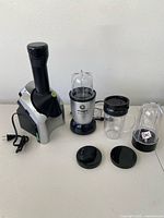 Magic Bullet blender with multiple accessories alongside Yonanas frozen fruit maker on a table.