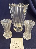 Three crystal items displayed: one large Orrefors vase with vertical fluting and scalloped edge, two smaller Fostoria Melissa ribbed bud vases with thumbprint bases. White paper with number 231 before them.
