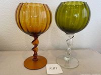 Pair of vintage Empoli art glass vases, one amber and one olive green with clear twisted stem, showing the full items side by side.