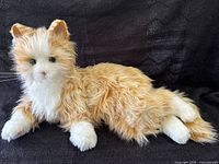 Side view of the plush robotic cat toy showing orange and white fur and overall shape