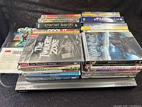 Stack of DVDs shown with various titles including Harry Potter, Star Wars (unopened), The Twilight Zone, Planet Earth, and others.
