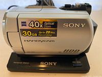 Side view of silver Sony Handycam DCR-SR42 showing 40x optical zoom, 30GB HDD, and Handycam branding with Sony logo, positioned on the included black Handycam Station dock.