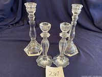 Front view of 4 crystal candlesticks including Tiffany & Co. and Bohemian styles on dark cloth background.