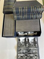 Two sets of antique stereographic plates, volumes labeled 'Palestine Vol. 1' and 'Vol. 2' and 'Four of the World', all stored in matching dark blue book-style cases with gold spine lettering, showing large quantity of plates in each case.