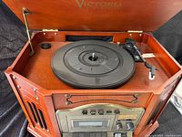 Top view of the record player with open lid showing the turntable and tonearm inside wooden cabinet.