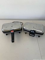 Two vintage kitchen appliances with chrome tops and black handles, placed side-by-side on a table.