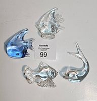 Four art glass fish paperweights and decor shown from above on a white surface for size reference.