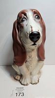 Front view of vintage blow mold basset hound coin bank showing its facial detail and front paws.