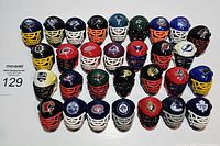Top-down group view of 29 Franklin mini hockey helmets representing various NHL teams arranged in rows showing front face cages and logos