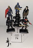 Front view of all seven GI Joe villain figures on display stands with some weapons in front, highlights figure details and stands