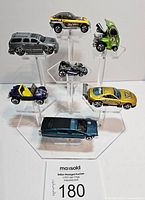Front view of the 7 Hot Wheels die-cast cars displayed on an acrylic stand showing variety of colors and styles.