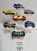 Eight Hot Wheels diecast vehicles displayed on clear stands: including a jet ski on a trailer, race cars in various colors and styles.
