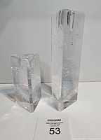 Two clear glass taper candle holders from front, showing size difference and internal textures and bubbles