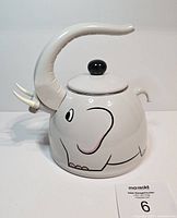 Side angle showing the full shape of the elephant teapot with trunk handle and painted facial details.