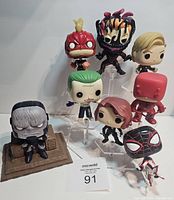 Photo of 8 Funko Pops displayed on stands with Kingdome Come Darkseid figure on a base, showing various characters in comic book style.