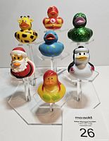 Front view showing seven Jeep rubber ducks on clear display stands against white background.