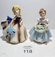 Front view of two lady planters with detailed painted faces, dresses, and floral accents.