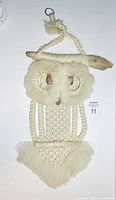 Full view of the macrame owl wall hanging showing the entire piece hanging and its texture.