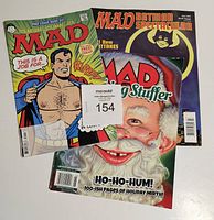 Three Mad Magazines lying overlapping showing covers: Superman parody on Free Comic Book Day cover, Batman special edition, and Santa Claus holiday issue.