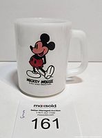 Front view of white vintage milk glass mug showing colorful Mickey Mouse image and text label on side.