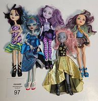 Front view of five Monster High dolls with distinct hairstyles and colorful clothing, one missing a hand